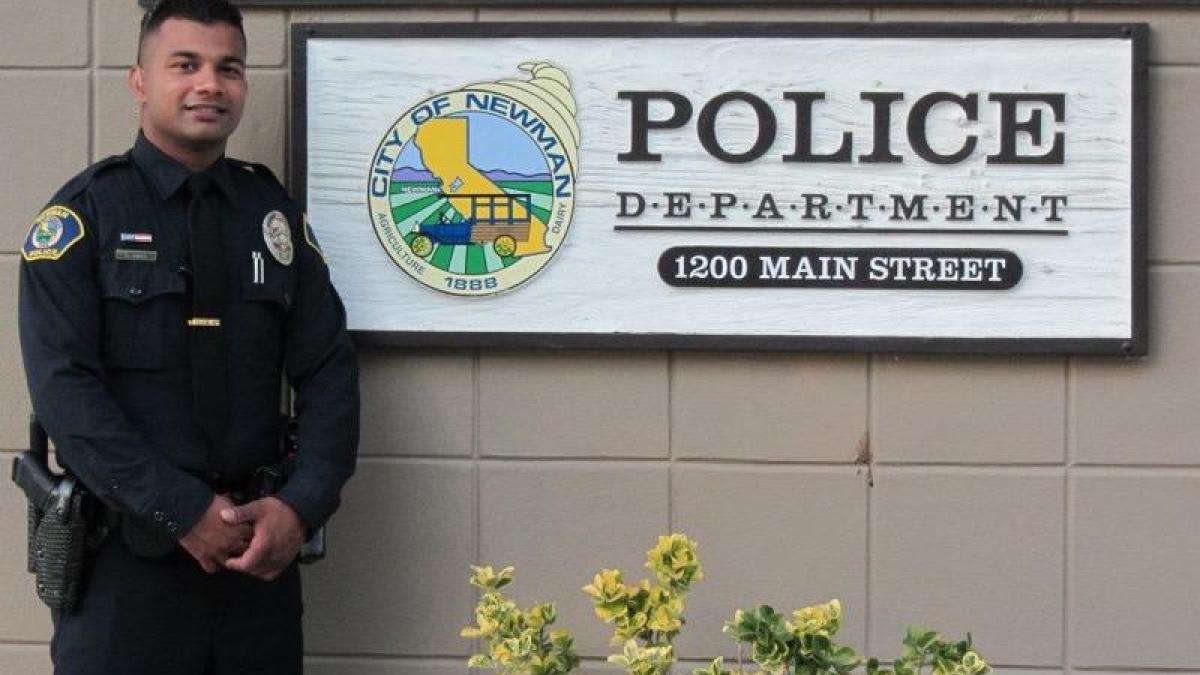 Police officer next to a Police Department sign