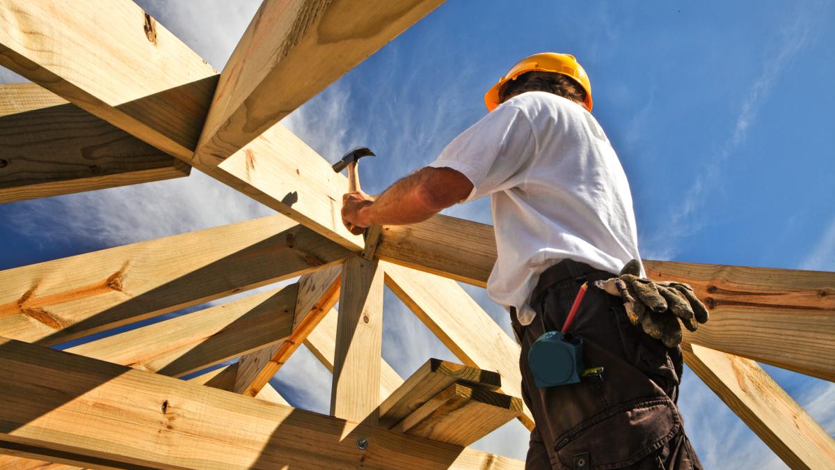 Worker hammering a nail into beam