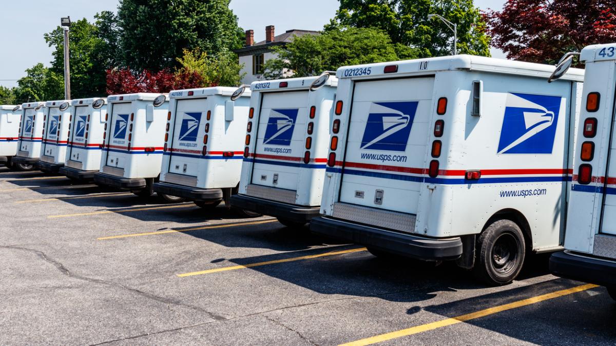 Row of USPS mail trucks parked in lot