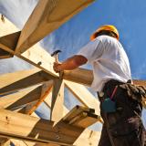 Worker hammering a nail into beam