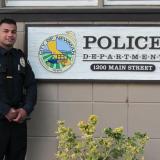 Police officer next to a Police Department sign