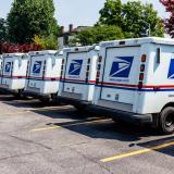 Row of USPS mail trucks parked in lot